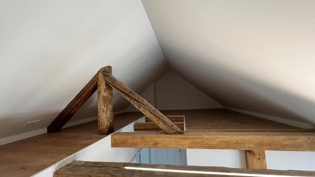 Dachboden Holzbalken Altbau Sanierung Obergeschoss Dachboden mit freiliegenden Dachkonstruktion aus Holz, weiße Dachschrägen, Holzfußboden, helles Tageslicht