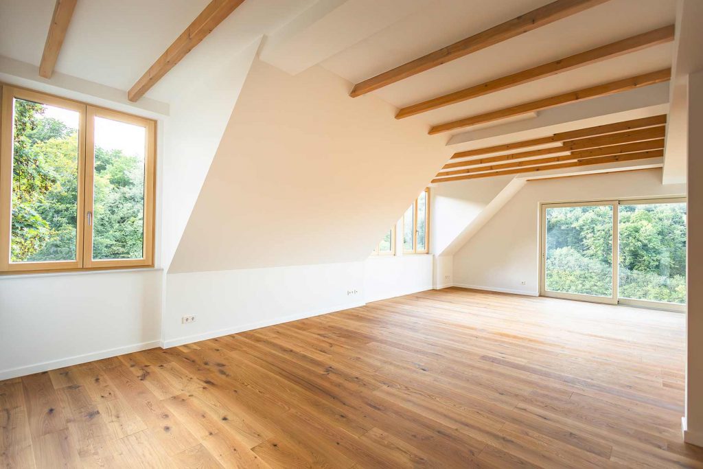 7I4A4988 Geräumiges Dachzimmer mit Holzbalken, Parkettboden und großen Fenstern zum Waldblick, helles Interieur