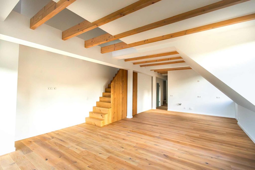 7I4A5000 Dachgeschosszimmer mit Holztreppe, Balkendecke und Parkettboden, weiße Wände, Türen zu Nebenräumen