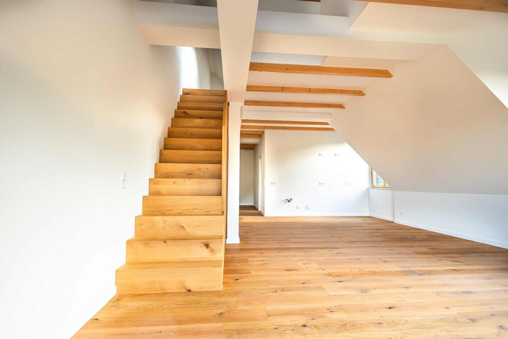7I4A5003 Dachgeschoss-Wohnraum mit Holztreppe, Balkendecke und Parkettboden, helle Wände