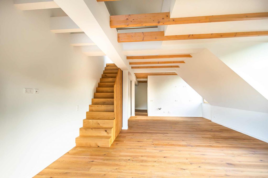 7I4A5006 Dachgeschossraum mit Holztreppe, Balkendecke und Parkettboden, offene Tür zu Nebenraum sichtbar