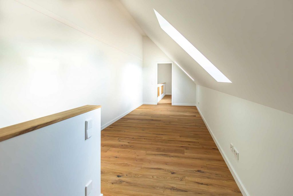 7I4A5015 Dachgeschoss-Flur mit Holzboden, weißen Wänden, Dachfenster und Türöffnung zum Nebenraum