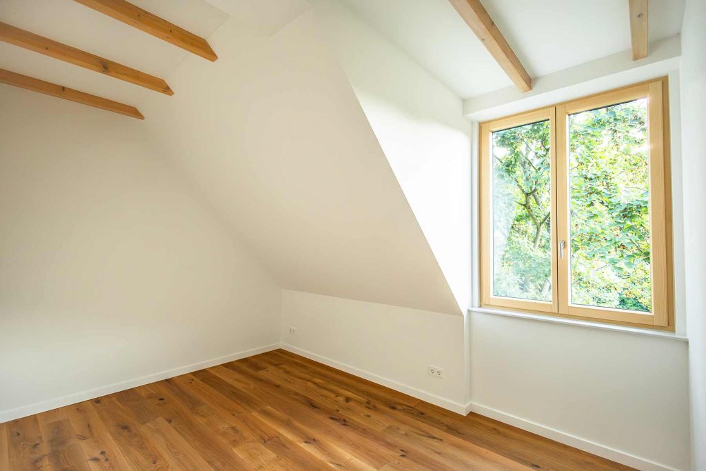 7I4A5049 Dachzimmer mit Holzbalken, Parkettboden und großem Fenster mit Waldblick