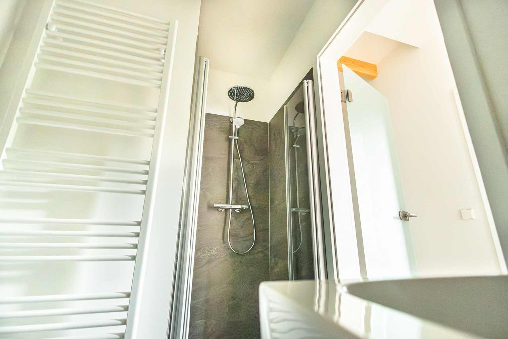 7I4A5072 Modernes Badezimmer mit Duschbereich, Glastür, Handtuchheizer links und Fenster mit Aussicht